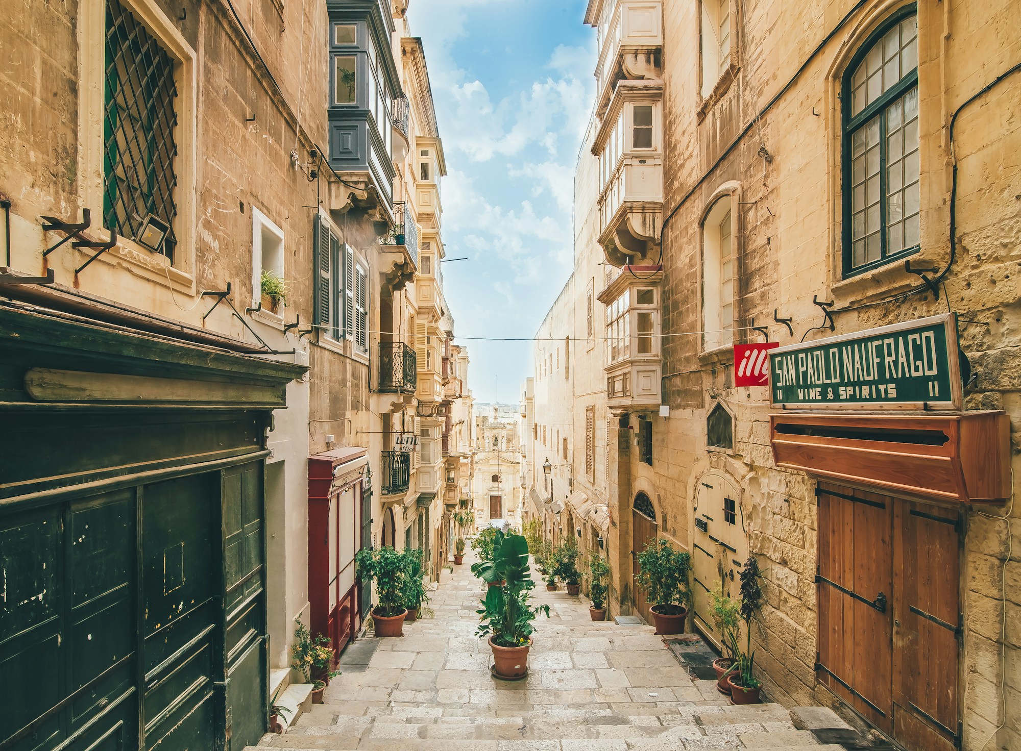 A quiet stepped street in Valletta with balconies and potted plants
